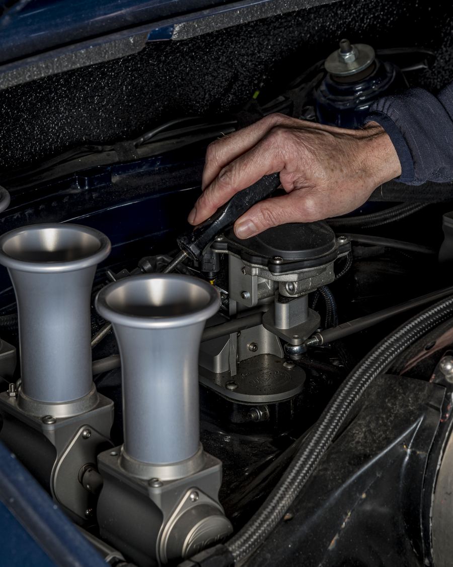 Hand adjusting a Rennen ITB system installed in a Porsche 911 engine bay