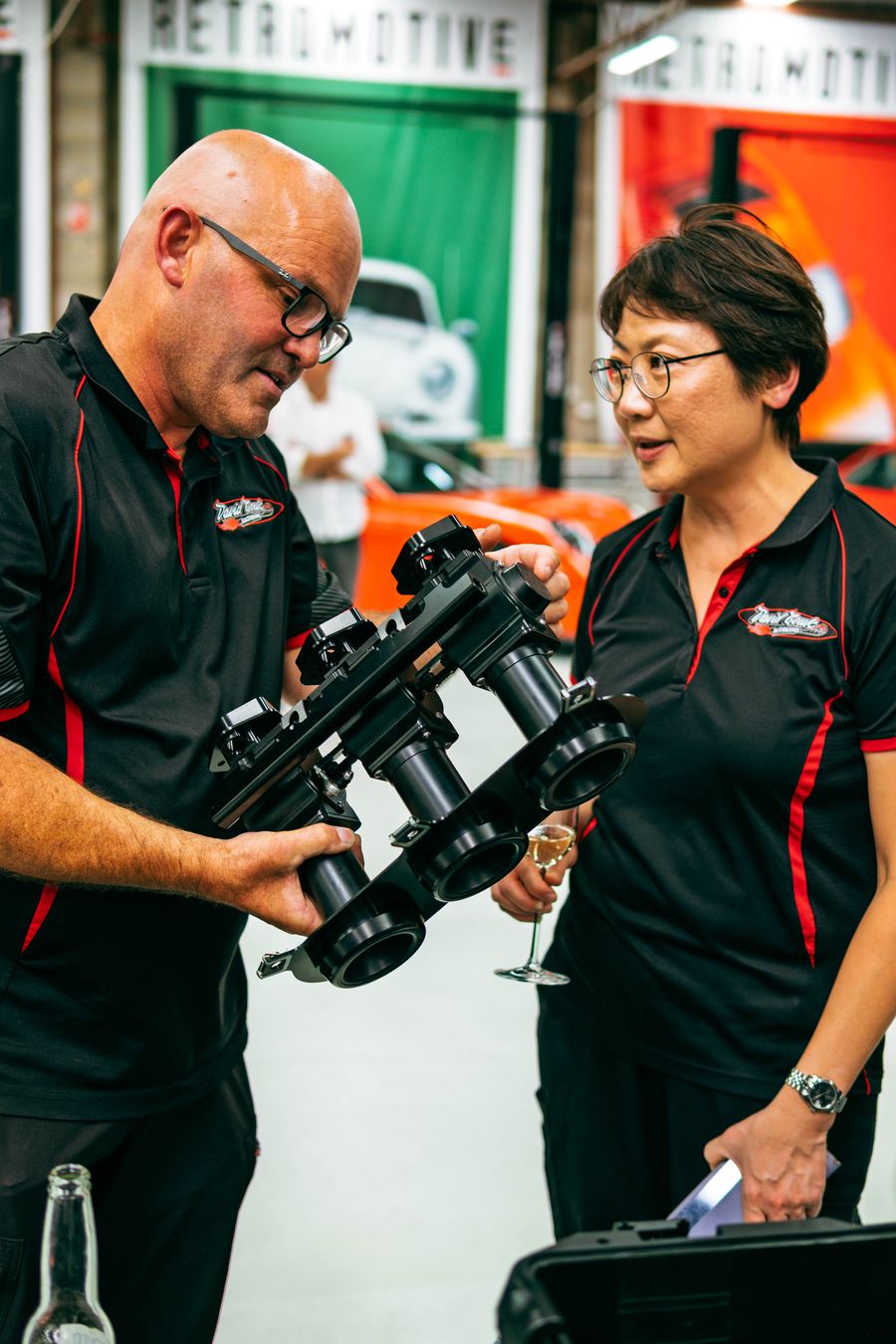 Trade visitors examining a Rennen ITB throttle body system at an event stand