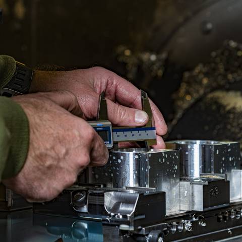 Measuring CNC-machined Rennen ITB billet components with digital calipers at the machine in Denmark